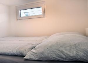 1 cama blanca en un dormitorio con ventana en Hausboot Fritz im Wangermeer, en Wangerland