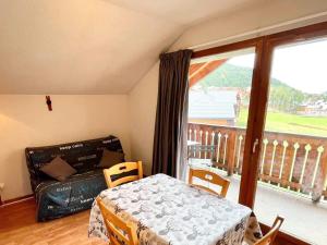 a living room with a table and a couch and a balcony at Studio cabine pour 4 avec parking gratuit à La Joue du Loup - FR-1-504-633 in Le Dévoluy