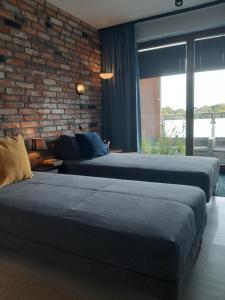a bedroom with two beds and a brick wall at Apartament nad Wilgą in Garwolin