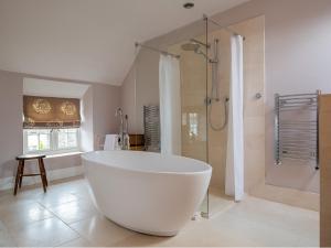 a large white tub in a bathroom with a shower at Stow House in Stow on the Wold +26 photos