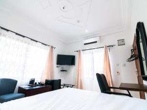 a bedroom with a bed and two chairs and a desk at KoKo Palm Inn LTD in Accra