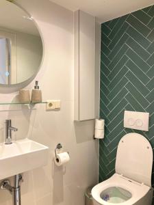 La salle de bains est pourvue de toilettes, d'un lavabo et d'un miroir. dans l'établissement B&B Berglust, à Rotterdam