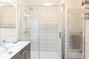a white bathroom with a shower and a sink at Stylish 2 bed apartment near Les Prodains Gondola in Morzine