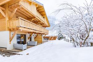 um chalé de madeira na neve com uma varanda em Stylish 2 bed apartment near Les Prodains Gondola em Morzine