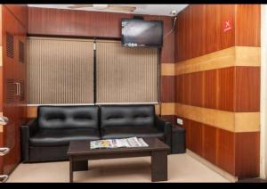 a living room with a black leather couch and a table at HOTEL MALABAR PLAZA in Chennai