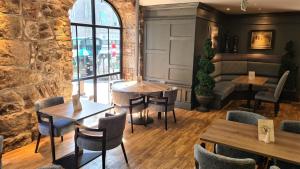 a restaurant with tables and chairs and a stone wall at Aberdeen Douglas Hotel in Aberdeen