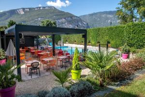 um pátio com mesas e cadeiras ao lado de uma piscina em Logis Le Relais de Sassenage em Sassenage