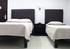 a bedroom with two beds with white comforters at Hotel Tampico Express in Ciudad Madero