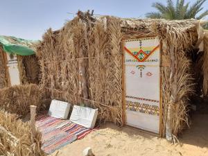 una cabaña con techo de paja con una puerta y un montón de paja en Hidigda Camp en ‘Izbat Ţanāţī
