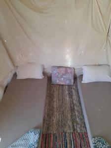 a bed in a tent with two pillows and a blanket at Hidigda Camp in ‘Izbat Ţanāţī