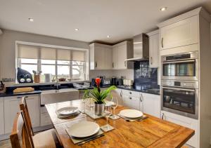 a kitchen with a wooden table with plates and flowers on it at Bwthyn Nant Bach in Dolbenmaen