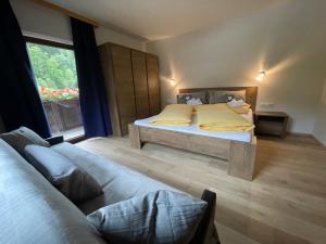 a bedroom with a bed and a couch and a window at Appartements Zellner in Alpbach