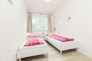 two beds in a white room with pink pillows at L4 - Ferienanlage Lindenstraße 1 - FERIENDOMIZIL HOLLICH in Grömitz