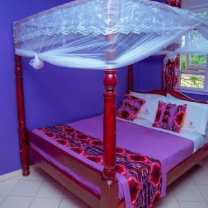 1 dormitorio con cama con dosel y paredes moradas en Richy Hotels and Safaris en Mbale