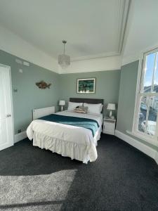 a bedroom with a large bed and two windows at Ivy Bank Guest House, Tenby in Tenby
