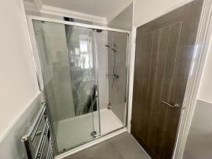 a shower with a glass door in a bathroom at Exquisite apartment, stone throw from the beach in Bournemouth