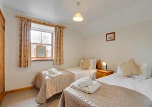 a bedroom with two beds and a window at Murmur y Ceri in Rhyd Lewis