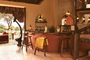 a bar in a room with stools and a table at Tawi Lodge in Amboseli