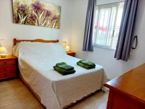 1 dormitorio con 1 cama y 2 toallas verdes en Ground Floor Apartment - Opposite pool C, en Playas de Orihuela