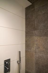 a bathroom with a tile wall with a shower at Prachtig royaal gastenverblijf in Schijndel