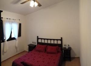 Cette chambre comprend un lit avec des draps rouges et un ventilateur de plafond. dans l'établissement Casa Rural el Argen, à Segorbe