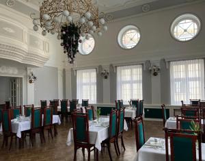 a dining room with tables and chairs and a chandelier at Hotel Wkra in Działdowo