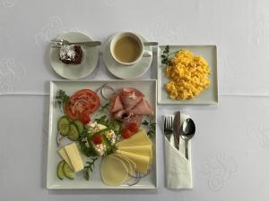 a table with three plates of food and a cup of coffee at Hotel Wkra in Działdowo +24 photos