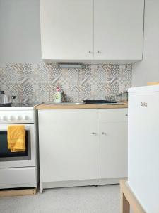 a kitchen with white cabinets and a stove at Pigeon apartment in Kuldīga