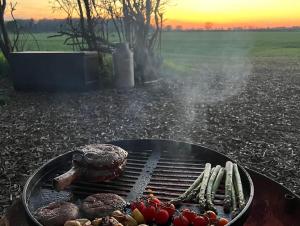 a grill with meat and vegetables on it with the sunset at The Warren, Hot Tub in Brackley