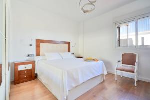 a bedroom with a white bed and a chair at PENTHOUSE NEAR BEACH AND MALAGA TOWN also monthly hire and long term RENTAL CAR AVAILABLE in Málaga