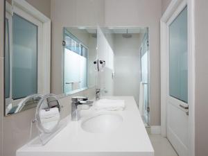 Baño blanco con lavabo y espejo en Cloud 9 Boutique Hotel and Spa, en Ciudad del Cabo