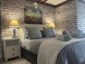 a bedroom with two beds and a brick wall at Ou Klipskuur Self-Catering Accommodation in Fraserburg