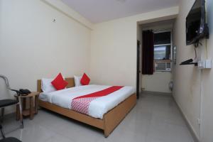 a bedroom with a bed with red pillows and a television at Mannat Residency in Ghaziabad