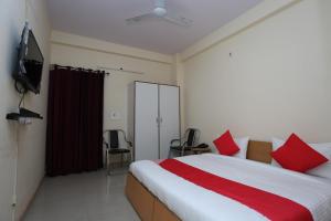 a bedroom with a bed with red pillows and a television at Mannat Residency in Ghaziabad +1 photo