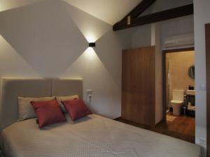 een slaapkamer met een bed met 2 rode kussens bij PATE'O Hostel & Suites in Ovar