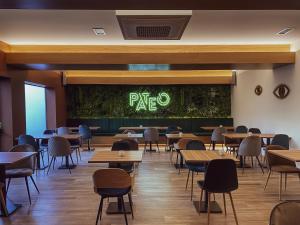 PATE'O Hostel & Suites في أوفار: غرفة طعام مع طاولات وجدار أخضر مع علامة البيتزا
