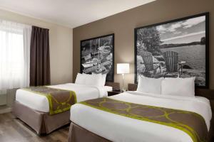 サーニアにあるSuper 8 by Wyndham Sarnia ONのベッド2台、テーブルと椅子が備わるホテルルームです。