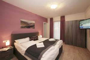 a bedroom with a large bed and a flat screen tv at Lake and Cityhotel Edelweiss - self Check in in Zell am See