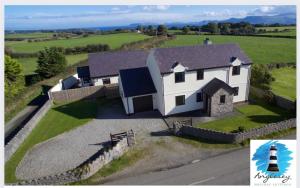 an aerial view of a white house with a lighthouse at 4 Bedroom Detached Farmhouse Mountain Views in Beaumaris