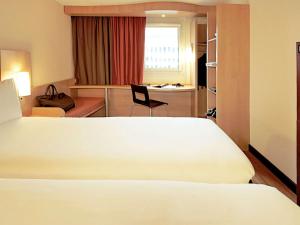 um quarto de hotel com uma cama branca e uma cadeira em ibis Loriol Le Pouzin em Le Pouzin