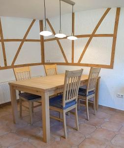stół jadalny z 4 krzesłami oraz sufit z belkami stropowymi w obiekcie Ferienwohnung am Hardtwald w mieście Heidenheim an der Brenz