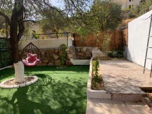 un giardino con un albero e un muro di pietra di Tayoon Host a Jerash