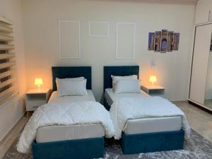 twee bedden in een kamer met twee lampen op tafels bij Tayoon Host in Jerash