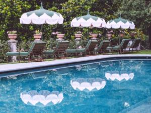 a swimming pool with chairs and umbrellas at Passalacqua in Moltrasio