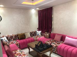 sala de estar con sofás y sofá rosa en اقامة العائلة en Nador