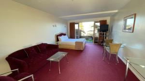- un salon avec un canapé et un lit dans l'établissement Chantillys Motor Lodge, à Taupo