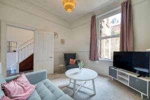 a living room with a couch and a tv and a table at Brent House - 4 bedroom home close to shops, harbour & beaches in Ilfracombe