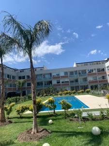 a resort with a palm tree and a swimming pool at Departamento Villa Los Remeros, Tigre in Tigre