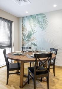 New fully serviced 1BR Apartment في العين: غرفة طعام مع طاولة وكراسي خشبية