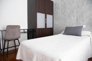 sypialnia z białym łóżkiem i krzesłem w obiekcie Hostal Tokio w Madrycie